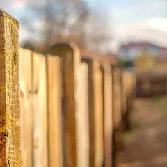 Drewniane sztachety tworzą ścieżkę. Zastanawiasz się, czy ogrodzenie trzeba zgłaszać? Warto sprawdzić przepisy.