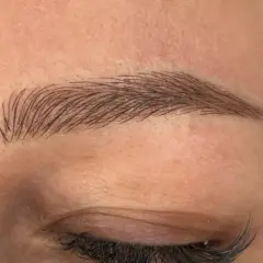 Efekt naturalnych brwi po zabiegu microblading. Delikatne włoski podkreślają kształt oka.