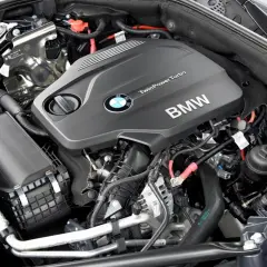 Silniki BMW F10 TwinPower Turbo. Widok na czarny, nowoczesny silnik z logo BMW i licznymi przewodami.