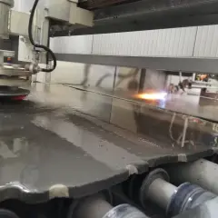 Macchina industriale esegue la fiammatura marmo, creando una superficie ruvida e antiscivolo.