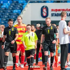 Piłkarze i sędziowie wchodzą na murawę stadionu.