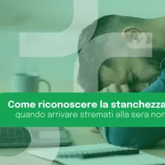Uomo esausto appoggiato alla mano, con laptop e taccuino. La stanchezza cronica può manifestarsi anche con un senso di spossatezza serale.