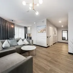 Nowoczesny apartament z szarą sofą, okrągłym stolikiem i widokiem na kuchnię.