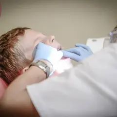 Chłopiec u dentysty, który wykonuje czyszczenie zębów.