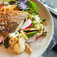 Delicioso pescado blanco crujiente con guarnición de verduras a la parrilla y rábano fresco.