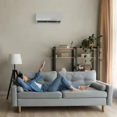 Soggiorno con pareti grigio moderno, divano comodo e aria condizionata. Perfetto per rilassarsi con un libro.