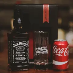 Zestaw na drinka: butelka Jack Daniel's, szklanka z logo destylarni i puszka Coca-Coli. Idealny na wieczór z klasycznym jack and coke.