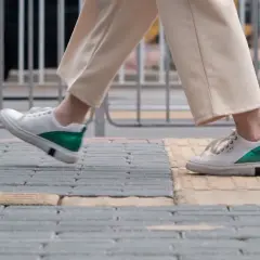 Białe sneakersy z zielonym akcentem na pięcie, idealne na spacer. Zastanawiasz się, jaki rozmiar buta francuski a polski wybrać?