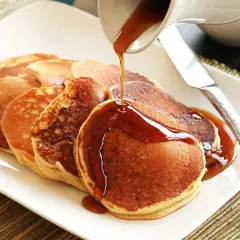 Pancakes dorati, preparati con bicarbonato al posto del lievito, vengono irrorati da uno sciroppo ambrato.