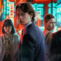 Fem personer poserar framför neonupplysta skyltar i Tokyo. En ung man i kostym blickar intensivt mot kameran, en scen som fångar essensen av "Tokyo Vice".