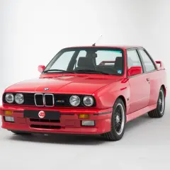 Klasyczne czerwone bmw e30 coupe z czarnymi felgami i emblematem M3. Ikona motoryzacji.