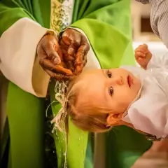 Un bébé est baptisé, de l'eau coule sur sa tête. Une étape importante, le baptême civil, une démarche pour la vie.