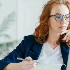 Kobieta w okularach z modną oprawką pracuje przy laptopie. Dofinansowanie do okularów może pomóc w zakupie stylowych i wygodnych oprawek.