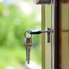 Llaves colgando de una puerta abierta, simbolizando el intercambio de casas entre particulares.