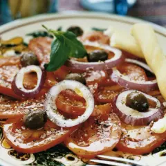 En läcker italiensk potatissallad med tomater, rödlök, oliver och basilika, serverad med grissini.