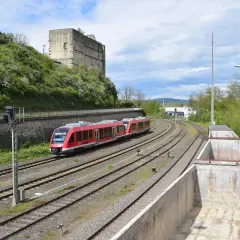 Roter Zug fährt auf Gleisen an einer Burgruine vorbei. br 640.