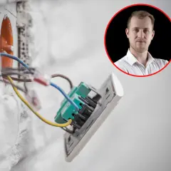 Prąd budowlany w ścianie, instalacja elektryczna w trakcie prac. W tle mężczyzna w białej koszuli.