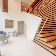 Nowoczesne wnętrze z białymi schodami i drewnianą ścianą. Fotograf architektury uchwycił minimalistyczny design i grę światła.