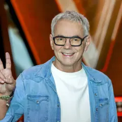 Robert Janowski, syn księdza, w dżinsowej koszuli i okularach, pokazuje znak pokoju.