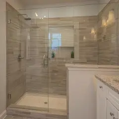 A modern bathroom featuring a spacious glass-enclosed shower with wood-look tile walls, a testament to a successful DIY shower tile installation.