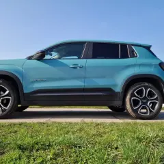 Turkusowy Jeep Avenger na tle błękitnego nieba. Z boku widoczna nazwa modelu i felgi. Idealne wymiary dla miejskiego SUV-a.