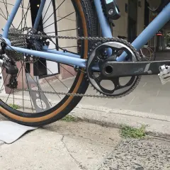 Błękitny rower z napędem Shimano, widok na tylne koło, kasetę i korbę.