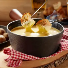 Un délicieux moment de partage autour d'une fondue savoyarde crémeuse, avec du pain croustillant trempé dans le fromage fondu.