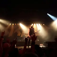 Koncert jednego z najsłynniejszych zespołów rockowych. Wokalista z basem na scenie, tłum szaleje.