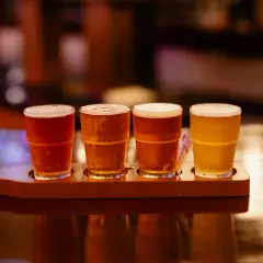 Quatre verres de bière, dont une rye IPA, sur un plateau en bois.