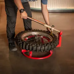 Persona usando una herramienta para cambiar neumatico moto.