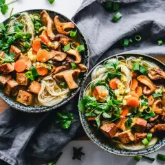 Två skålar med nudlar, svamp, morötter och krispiga tofu-bitar. Ett perfekt tofu recept för en värmande måltid.
