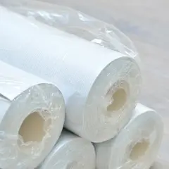 Rolki białej raufazy, gotowe do metamorfozy wnętrza. Delikatna faktura zapowiada przytulną atmosferę.