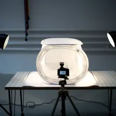 Studio do fotografii produktowej z aparatem na statywie, dyfuzorem i dwoma lampami tworzącymi światło kontrowe.