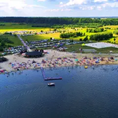 Tętniące życiem jeziora na Dolnym Śląsku latem. Plaża pełna ludzi, namioty, parkingi i zieleń wokół.