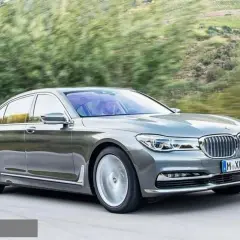 Eleganckie BMW 730d sunie po krętej drodze wśród zieleni.