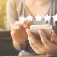 Une personne utilise son smartphone pour laisser un avis 5 étoiles, un élément clé du marketing digitale.