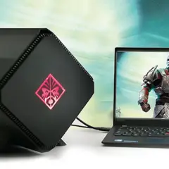 Czarna, futurystyczna karta graficzna zewnętrzna do laptopa z podświetlanym logo OMEN, obok laptopa z grą.