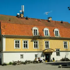 Gult hus med orange tak, "Ut Sikten" skylt. Finnhamn vandrarhem, en plats för avkoppling och naturupplevelser.