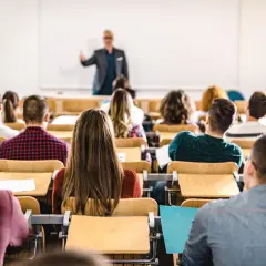 Dozent spricht vor Studenten im Hörsaal. Viele junge Leute, die vollzeit arbeiten und studieren, sind aufmerksam.