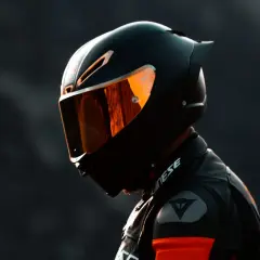 Motociclista con casco integral deportivo, uno de los tipos de cascos de moto, con visor naranja reflectante.