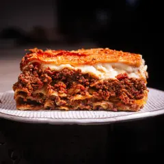 Ein Stück Lasagne mit Hackfleisch und Käse auf einem Teller. Perfekt, wenn man sich fragt, wie lange Lasagne im Ofen braucht.
