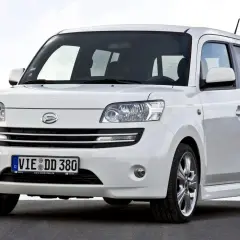Biały Daihatsu Materia z niemieckimi tablicami rejestracyjnymi stoi na ciemnej nawierzchni.