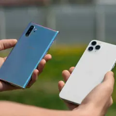 Dwie dłonie trzymają telefony: niebieski Samsung i biały iPhone. Który wybierasz?