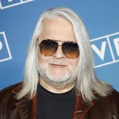 Artur Gadowski, wokalista IRA, w okularach przeciwsłonecznych i skórzanej kurtce, na tle niebieskim z logo "VP".