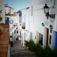 Hombre mira callejuela blanca en Frigiliana. Aquí puedes encontrar dónde comer en Frigiliana, con un bar y restaurante.