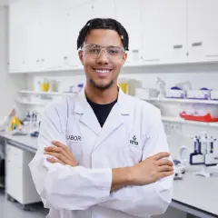 Junger Mann im Chemielabor, bereit für neue chemielaborant stellenangebote. Im Hintergrund eine Kollegin bei der Arbeit.