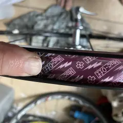 Close-up of a finger pressing down on Muc-Off tubeless rim tape, showing the process of how to tape tubeless rims for a secure seal.