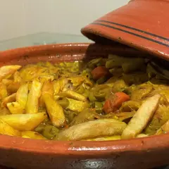 Un plat de tajine poulet olive, avec des pommes de terre dorées et des carottes, prêt à être dégusté.
