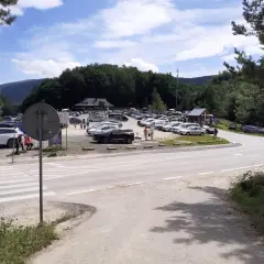 Duży parking na przełęczy wyżniańskiej, pełen samochodów podziwiających górskie krajobrazy.