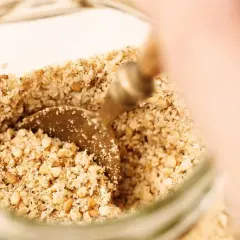 Un cucchiaino raccoglie il gomasio, un condimento a base di semi di sesamo tostati e sale, perfetto per insaporire i tuoi piatti.